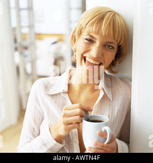 Teen girl holding tasse de café, sticking tongue out at camera Banque D'Images