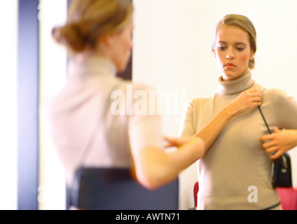 Femme au miroir à sac à main. Banque D'Images