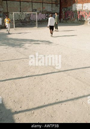 Les hommes des coups de ballon de soccer sur dirt field Banque D'Images