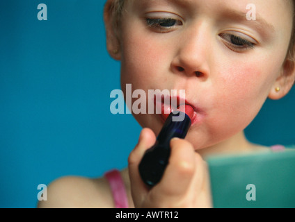 Petite fille de mettre du rouge à lèvres, close-up Banque D'Images