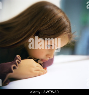 Girl leaning on table, side view Banque D'Images