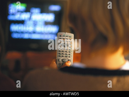 Jeune garçon avec télécommande dans la main regardant la télévision, vue arrière, Close up Banque D'Images