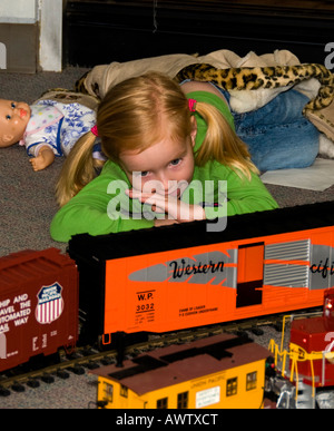 Une jeune fille regardait un train miniature exécuté sur une piste, à tous Banque D'Images