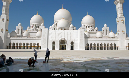 Les ouvriers travaillent à l'ombre sur le sol en marbre de la cour de la mosquée Sheikh Zayed, à Abu Dhabi, aux Émirats arabes Unis, peu après son ouverture au public. Banque D'Images