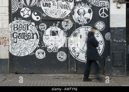 Un homme passe devant un graffitied wall à Brixton, au Royaume-Uni. Banque D'Images