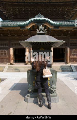 Woman waving fumer sur elle-même à brûleur à encens dans Butsuden Kenchoji Temple bouddhiste Zen à Kamakura au Japon Banque D'Images