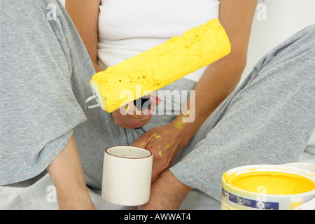 Jeune femme était assise sur le plancher holding paint roller Banque D'Images