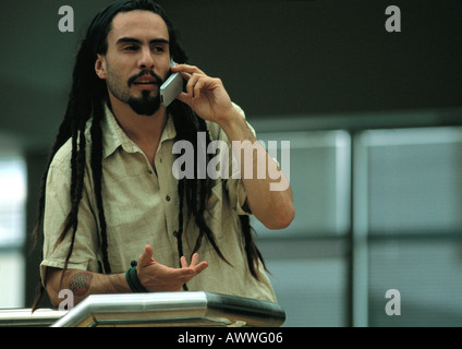 Man talking on cell phone, appuyé contre le rail Banque D'Images