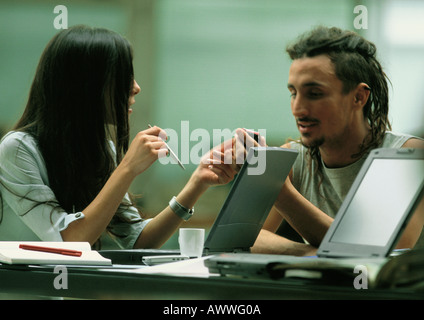 L'homme et la femme assis avec les ordinateurs portables, parler Banque D'Images