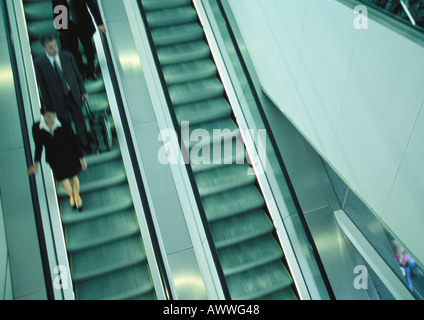 Les gens d'affaires sur l'escalator qui descend, brouillées, high angle view. Banque D'Images