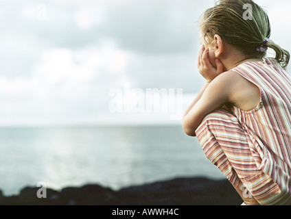 Girl crouching, mer en arrière-plan, vue arrière Banque D'Images