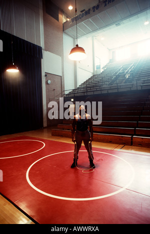 Portrait d'un athlète afro-américain fatigué dans un réservoir noir et shorts avec une corde à sauter dans une salle de sport rétro sous une lumière vive. Banque D'Images