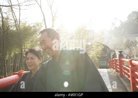 Vieux couple standing on bridge dans jardin, laughing Banque D'Images