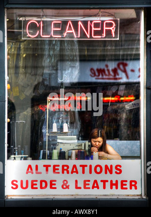 Femme dans un nettoyeur à sec sur mesure store front window travaillant par couleur vertical de la machine à coudre Banque D'Images