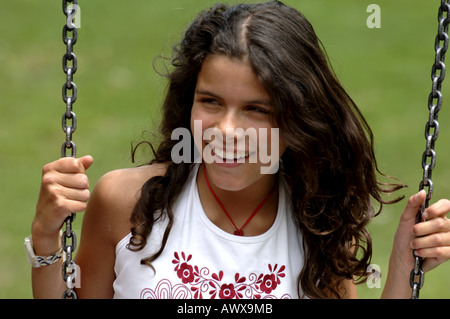 Smiling dark-haired Girl on a swing Banque D'Images