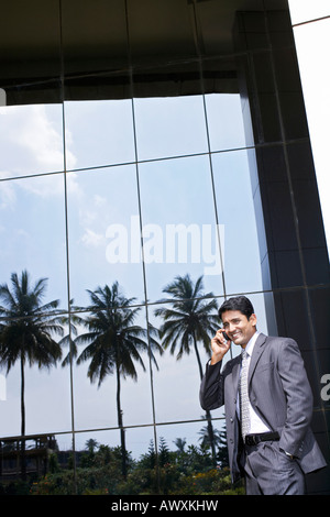 Business man sitting on porte-documents à l'aide de téléphone mobile en ville Banque D'Images