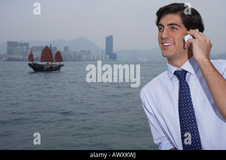 Man talking on mobile, traditional Chinese junk boat en arrière-plan Banque D'Images