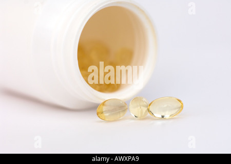 Capsules liquide clair s'échappant d'une bouteille sur le côté Banque D'Images