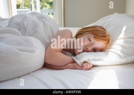 Portrait of Girl (5-6) Lying in Bed, smiling Banque D'Images