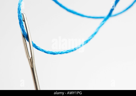 Fil bleu passant par chas de l'aiguille, close-up Banque D'Images