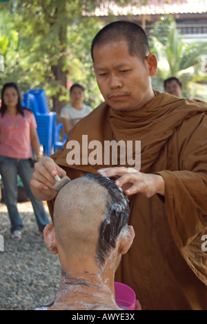 Moine bouddhiste thaï utilise un rasoir pour se raser la tête d'une jeune Thai man, une partie de l'ordination d'un moine novice Banque D'Images