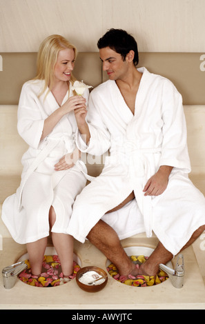 Un jeune couple bénéficiant d'un bain de pieds avec des pétales de rose Banque D'Images