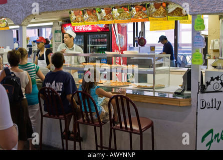 Les gens d'attente et les enfants assis à un salon de pizza Banque D'Images