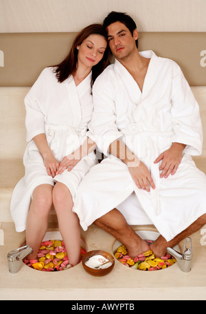 Un jeune couple bénéficiant d'un bain de pieds avec des pétales de rose Banque D'Images