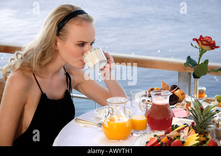 Jeune femme ayant le petit déjeuner sur la terrasse de l'hôtel Banque D'Images