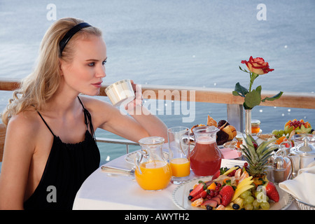 Jeune femme ayant le petit déjeuner sur la terrasse de l'hôtel Banque D'Images