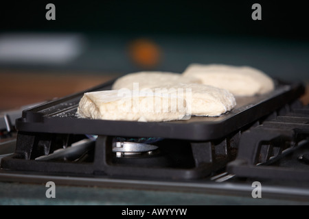 La cuisson du pain traditionnel irlandais de soude sur une cuisinière à gaz modernes sur une plaque pan Banque D'Images