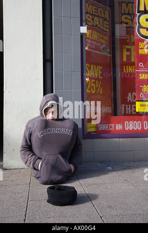 Les sans-abri en Écosse. Vente 'must End Soonn'  Homeless Street mendiant, sweat à capuche, dormeur rude. Un tramp assis dans le centre-ville de Dundee, Écosse Royaume-Uni Banque D'Images