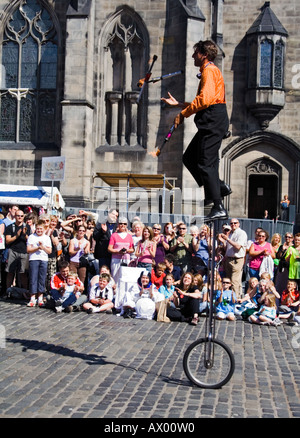 Artiste de rue sur un monocycle juggling fire clubs lors de la Royal Mile Edinburgh Festival Fringe, en Écosse. Banque D'Images