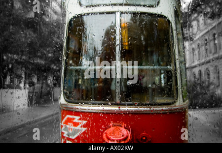 Un tram qui traversent une rue bordée d'un jour de pluie à Vienne, Autriche. Banque D'Images