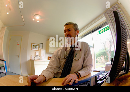 Homme blanc anglais médecin généraliste médecin de famille consulting avec stéthoscope et computer in office prix Angleterre GO UK Banque D'Images