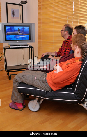 Family sitting on couch watching TV Banque D'Images