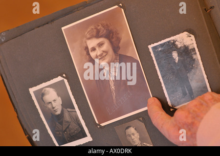 Femme âgée à la recherche par album photo rempli de vieux portraits de famille Banque D'Images