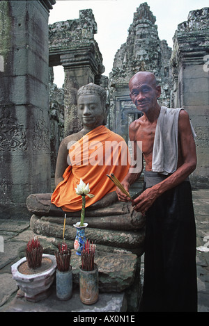 Portrait d'un moine sympathique tendant à un temple avec une robe safran à l'image du Bouddha Bayon Angkor Thom au Cambodge Banque D'Images