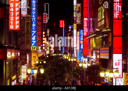 Scène mouvementée la nuit avec de nombreux signes lumineux lumineux et les gens qui marchent dans la rue à Shinjuku, Tokyo, Japon. Banque D'Images