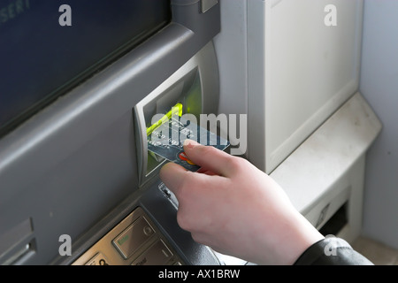 Une femme d'insérer sa carte de débit à un guichet automatique Banque D'Images