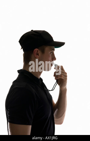 Vue de côté studio portrait d'un arbitre qui souffle dans un sifflet Banque D'Images