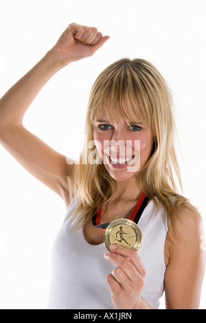 Une femme tenant une médaille d'or et d'élever son poing dans la célébration Banque D'Images