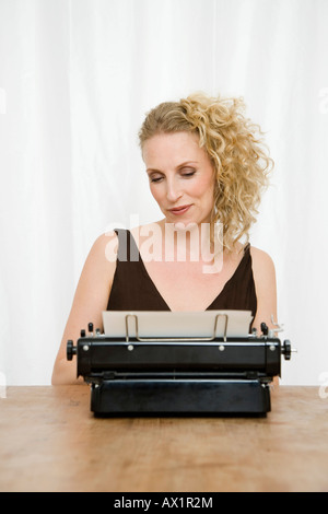 A mid adult woman sur un document dans une vieille machine à écrire à l'ancienne Banque D'Images