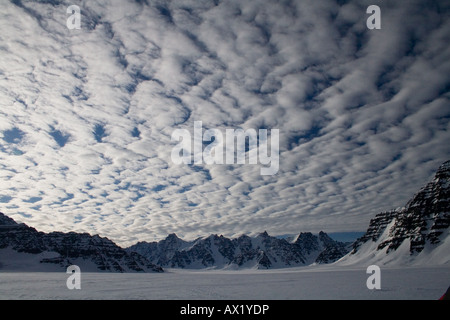 Le maquereau nuages sur une chaîne de montagnes et des glaciers du Groenland météo signalisation modifier Banque D'Images