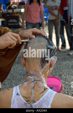 Moine bouddhiste thaï utilise un rasoir pour se raser la tête d'une jeune Thai man, une partie de l'ordination d'un moine novice Banque D'Images