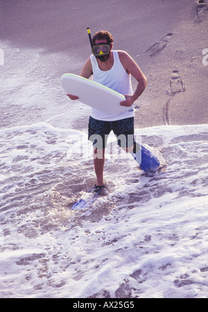 Homme excentrique avec boogie board at beach Banque D'Images