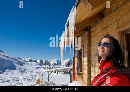 Jeune femme au soleil, assis à l'extérieur d'un chalet, les glaçons Banque D'Images