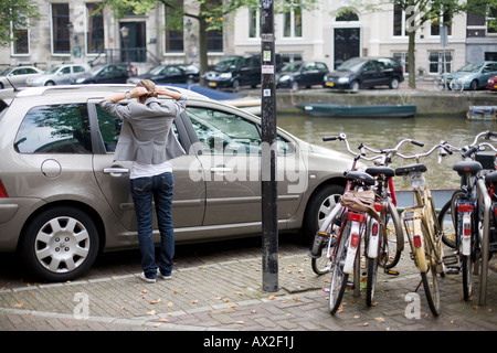 Quatre vélos garés sur une allée et une fille se coiffer près d'une voiture garée sur le bord d'une rivière situé dans la ville Banque D'Images