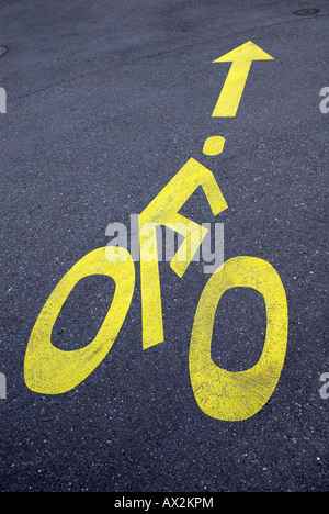 Cycliste peint jaune signe sur la route goudronnée Banque D'Images