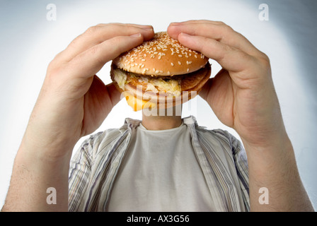 Burger Man, Man Eating Hamburger qui couvre sa tête Banque D'Images